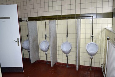 <p>Urinoirs met granieten 'schaamplaten' uit 1964. Het vertrek is afgewerkt met wandtegels en rode, dubbel hardgebakken vloertegels. </p>
